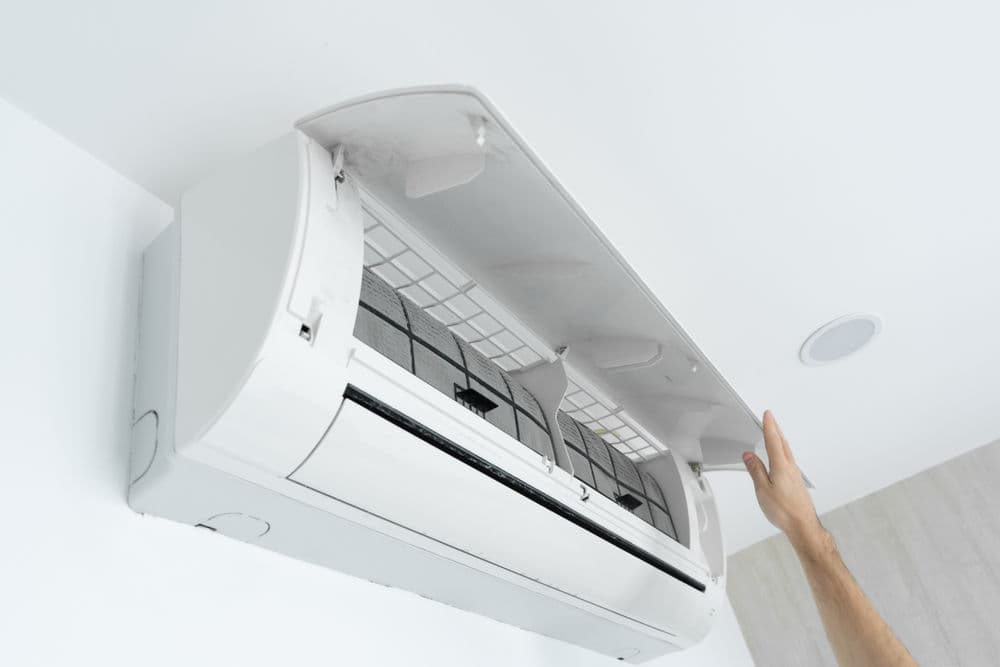Person opening an air conditioning unit for maintenance or cleaning.