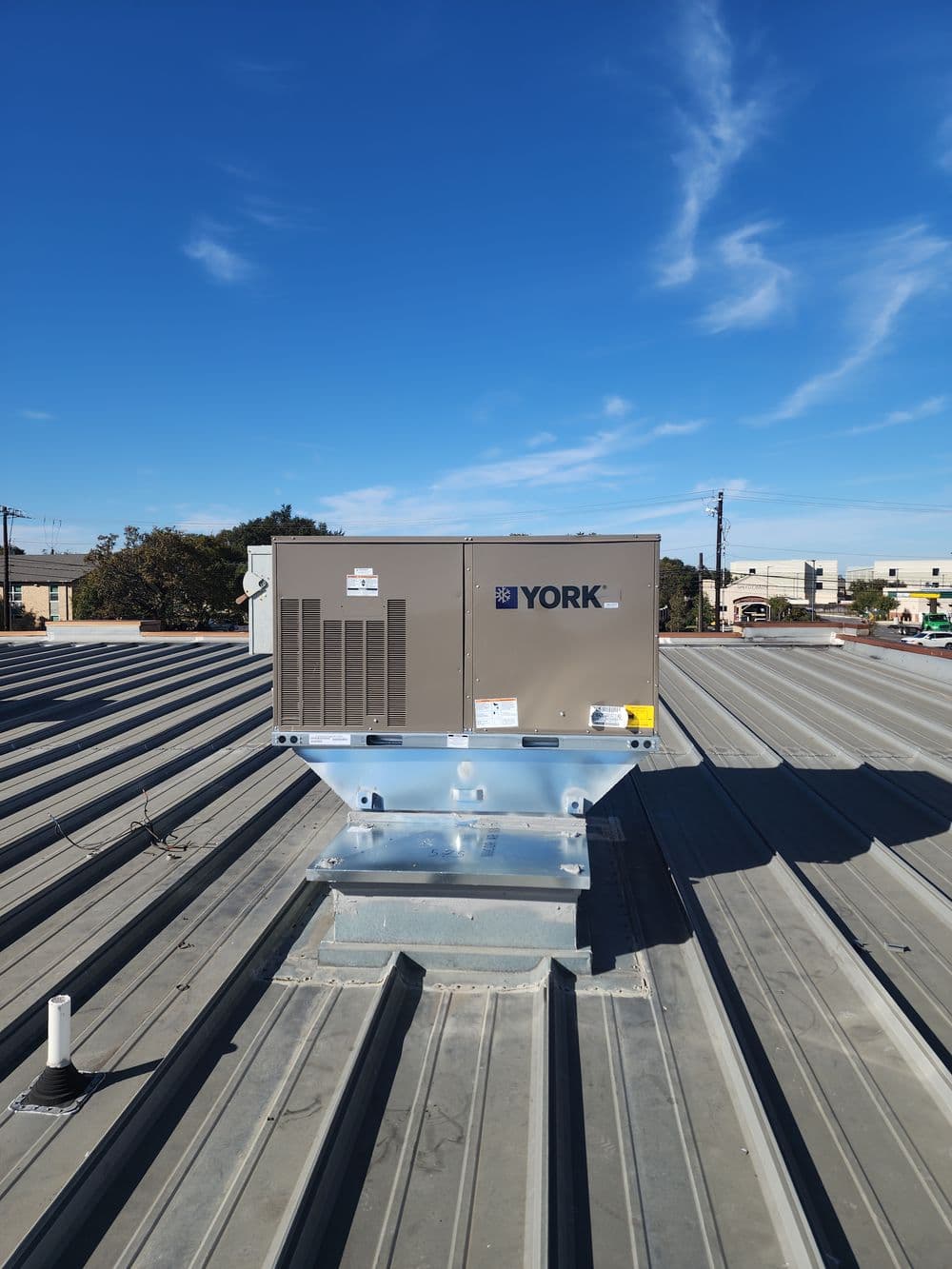 YORK rooftop HVAC unit on a metal roof under a clear blue sky.