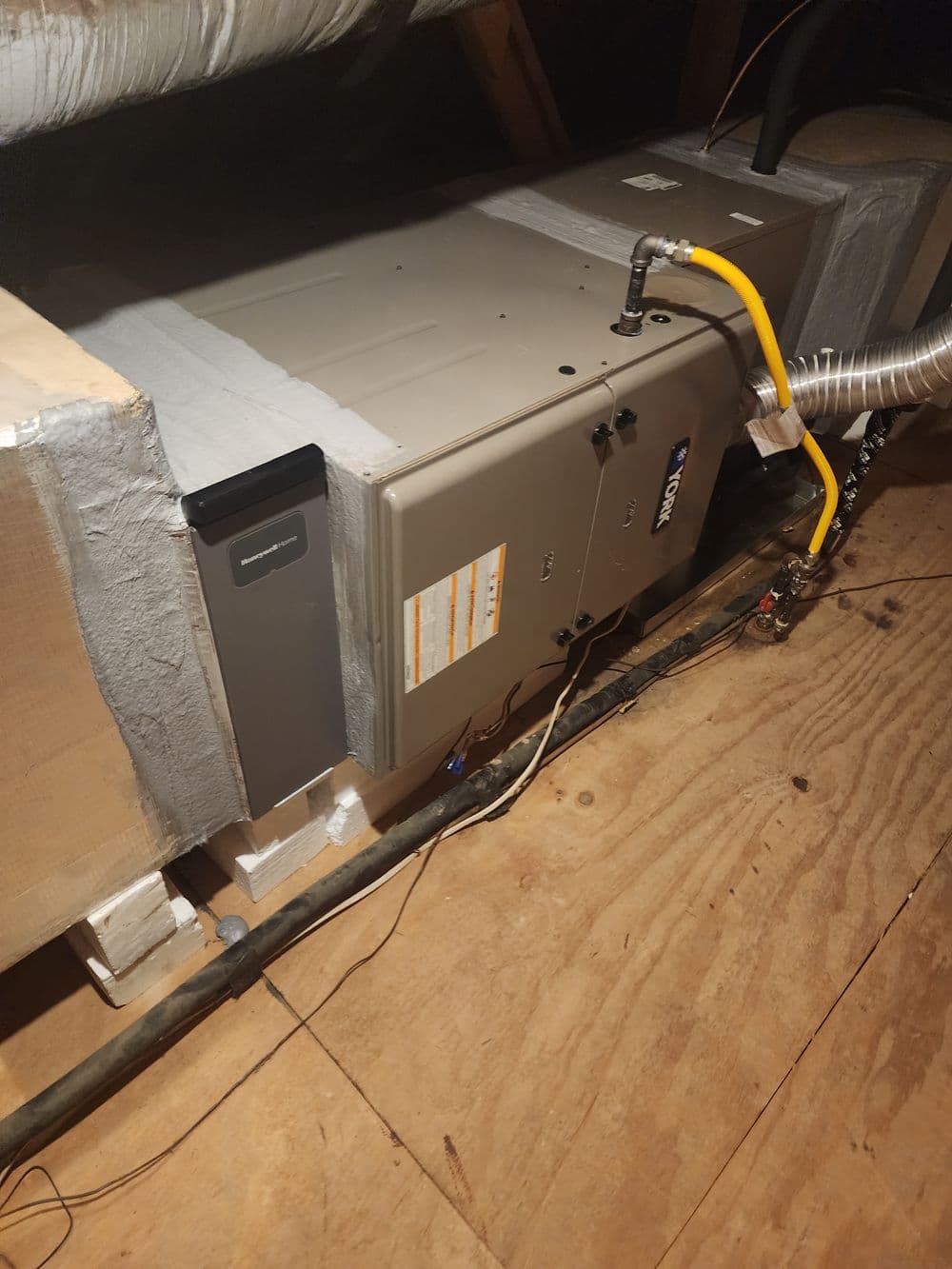 Furnace installation in attic with ductwork and electrical connections visible.