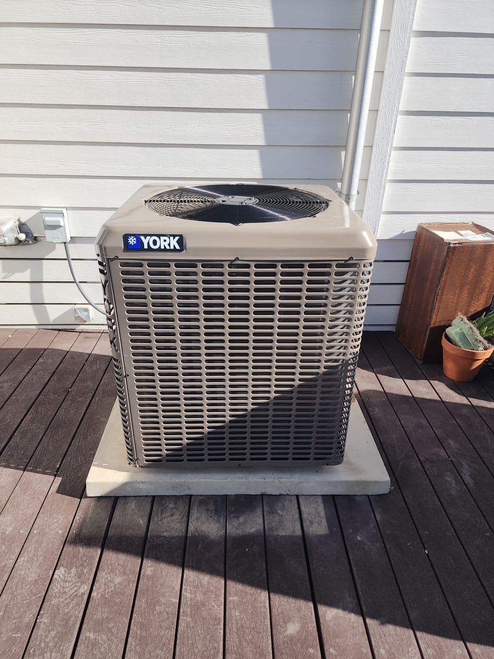 York air conditioning unit on a wooden deck, providing outdoor cooling solutions.