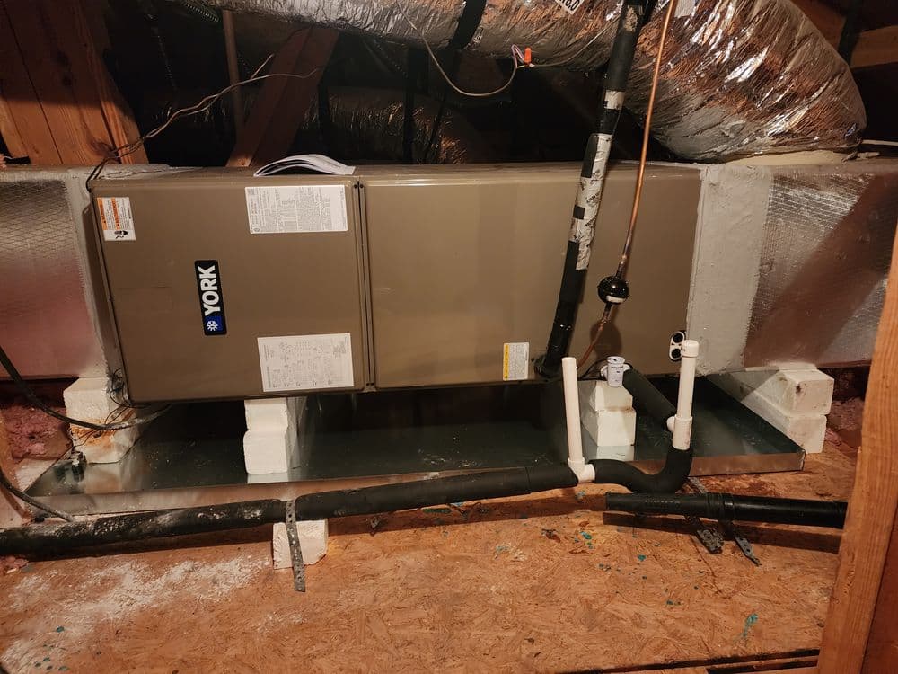 York HVAC system installed in attic with ductwork and piping visible. Energy-efficient heating.