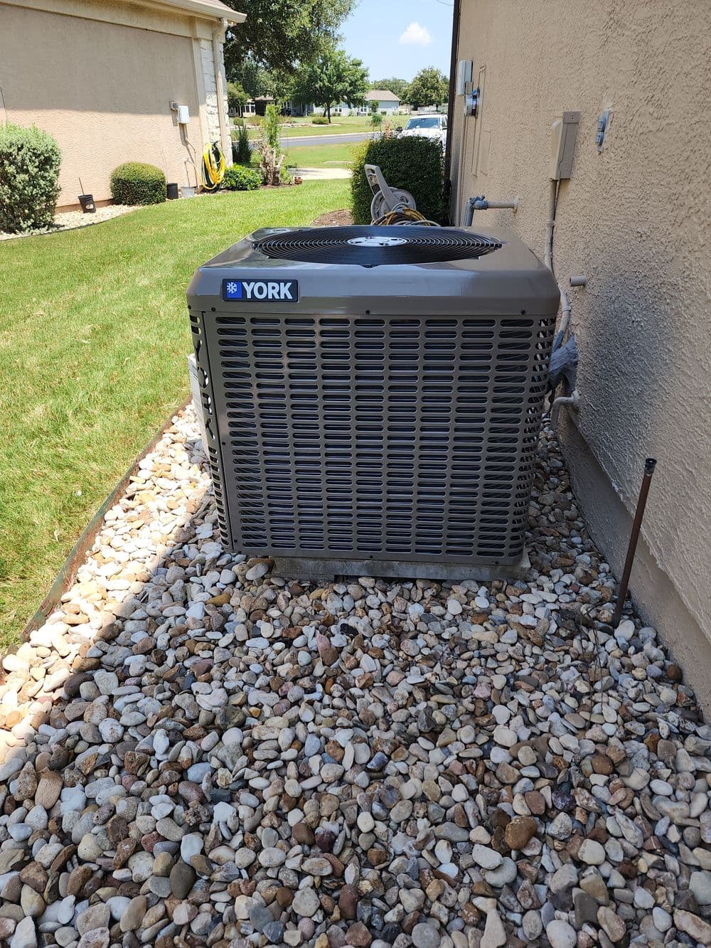 York air conditioning unit on gravel landscape beside a residential building.